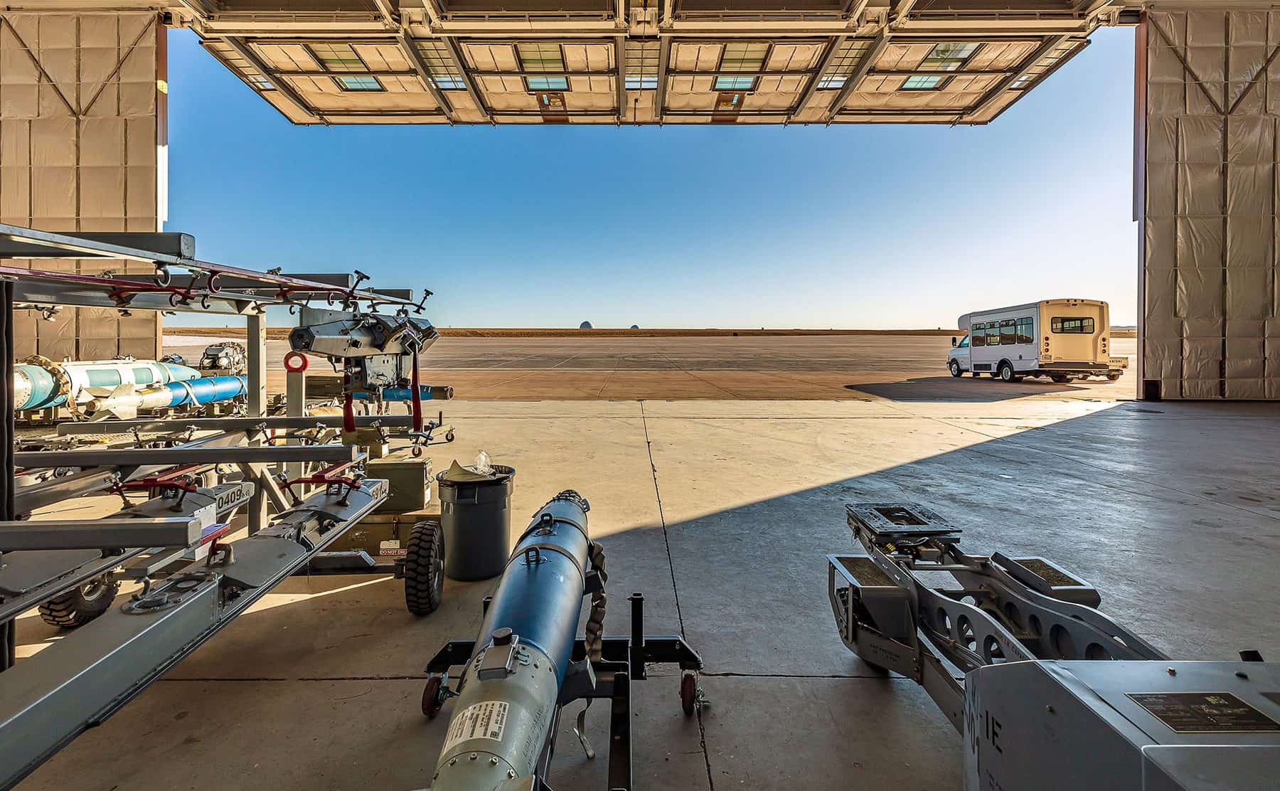 From inside the half open hangar looking out to a blue sky. Airplane components lay in hangar.