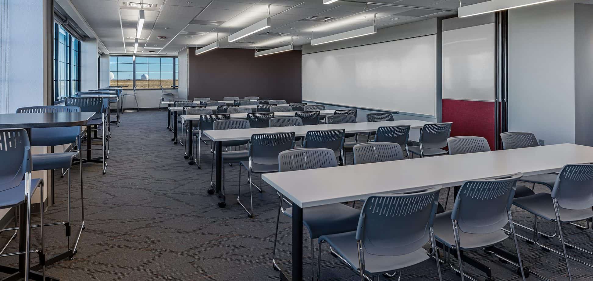 Training room with long tables and chairs. At the end of the room is a large window.
