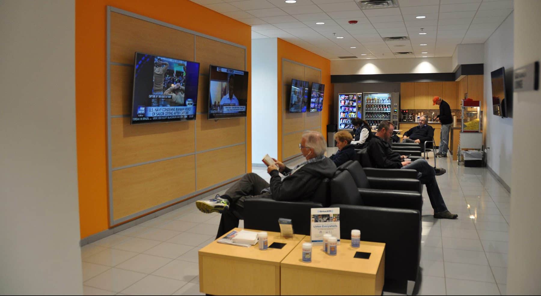 Communal space at the Ed Bozarth Chevrolet. People are sitting in nice chairs watching TV.