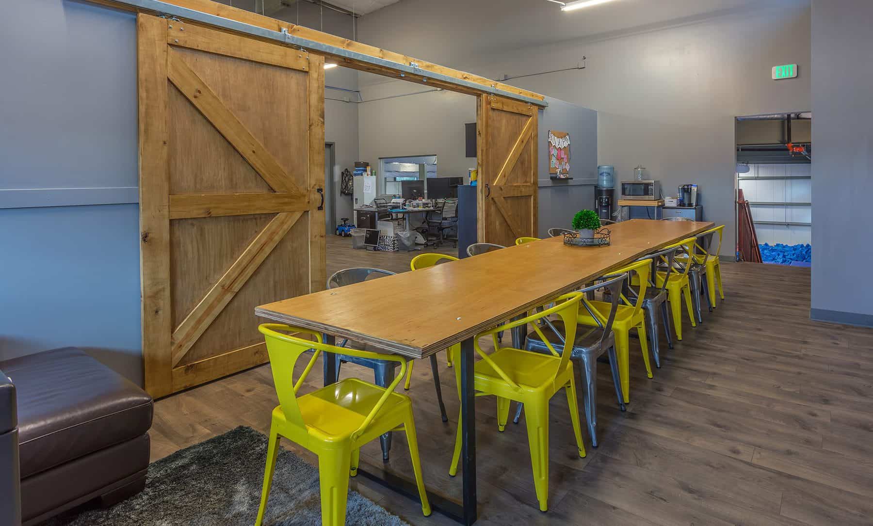 Large wooden sliding doors with a long wooden table with yellow chairs.