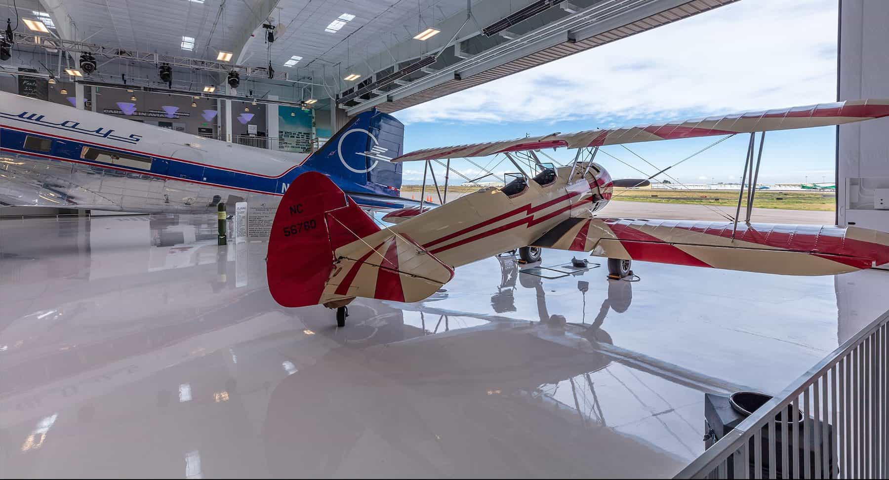 A biplane sitting in the open hangar of the Wings of the Rockies, Blue Sky Gallery designed by D2C Architects