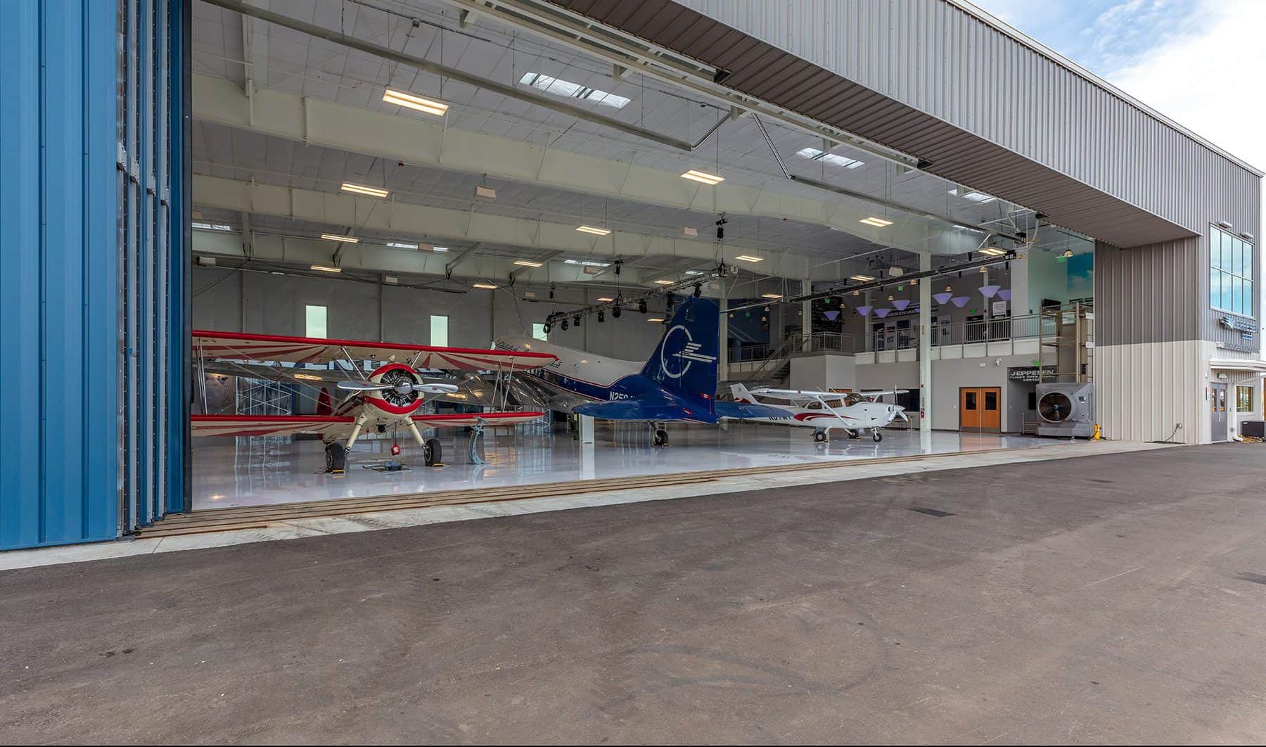 View from the outside looking in at an open hangar with multiple planes inside