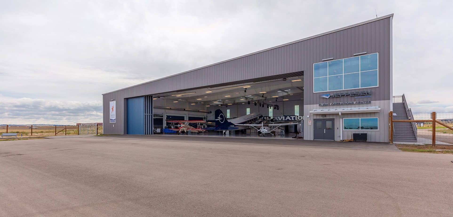 Wings Over the Rockies Blue Sky Gallery shown from the outside looking in from 75 meters away. The hangar doors are open.