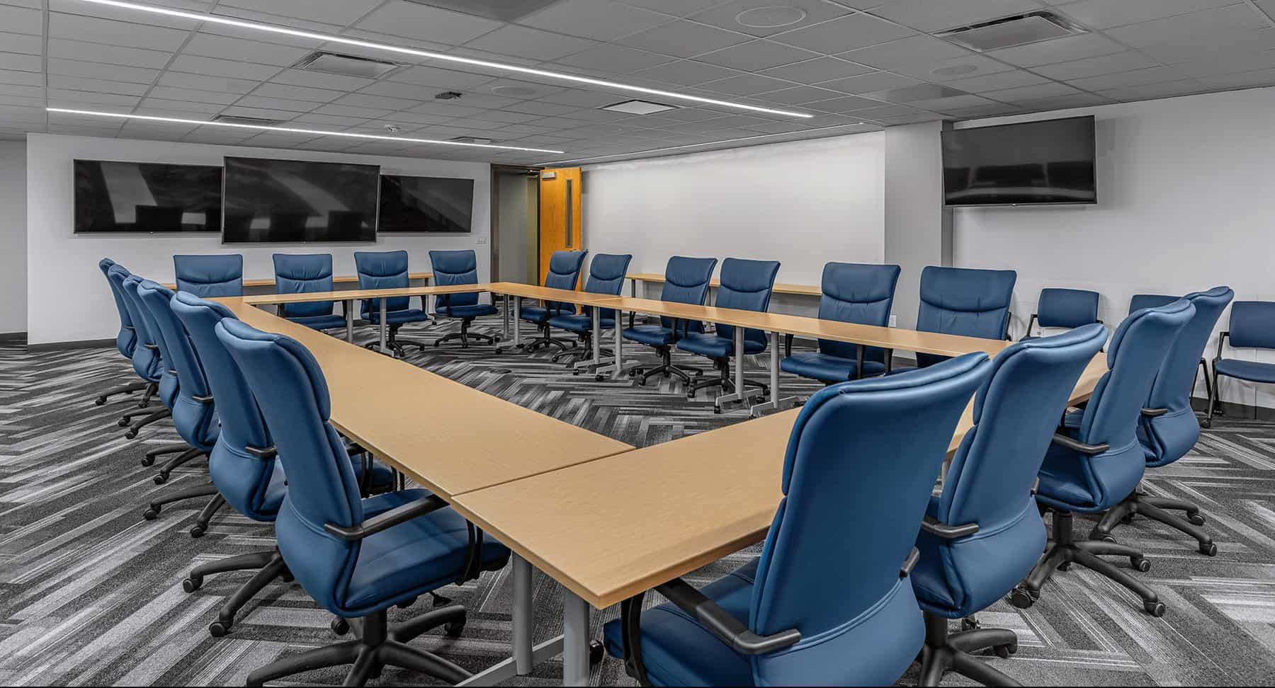 Training and Emergency Operations Center Conference room with a large table in the center that can be multi-functional depending on the use of the room. Blue chairs sit around the outside of the table.