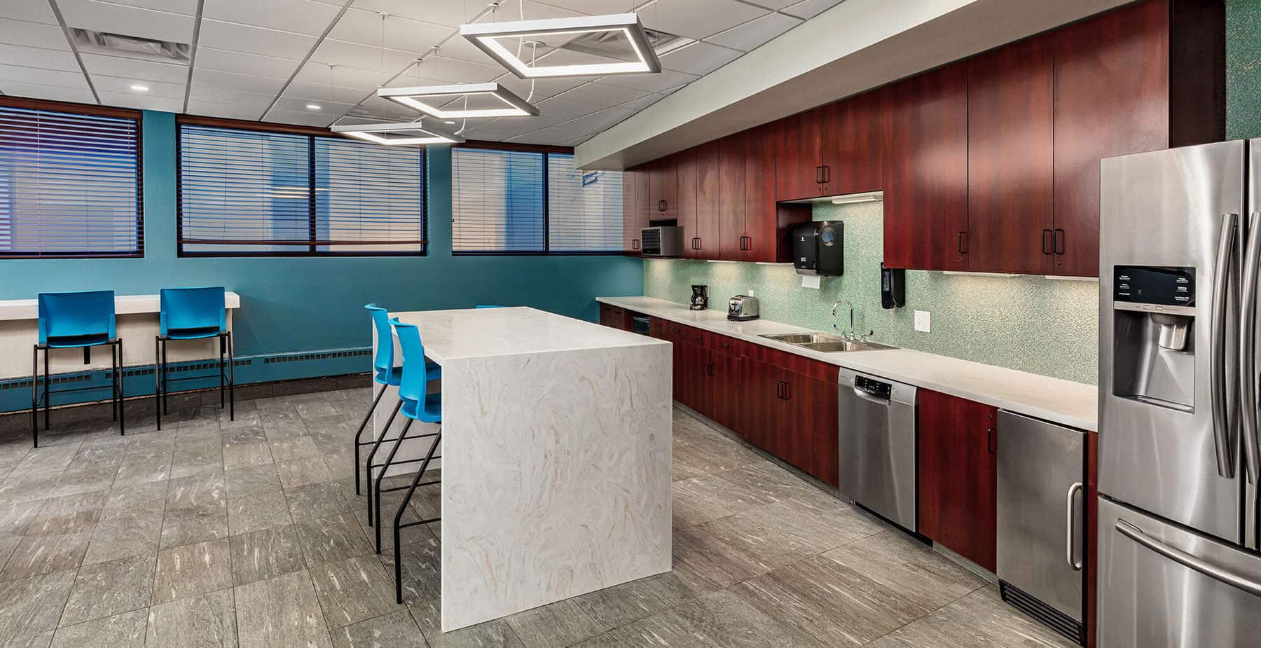 The kitchen / break room of The City of Greeley City Hall, includes modern kitchen utilities and high top tables and seating.