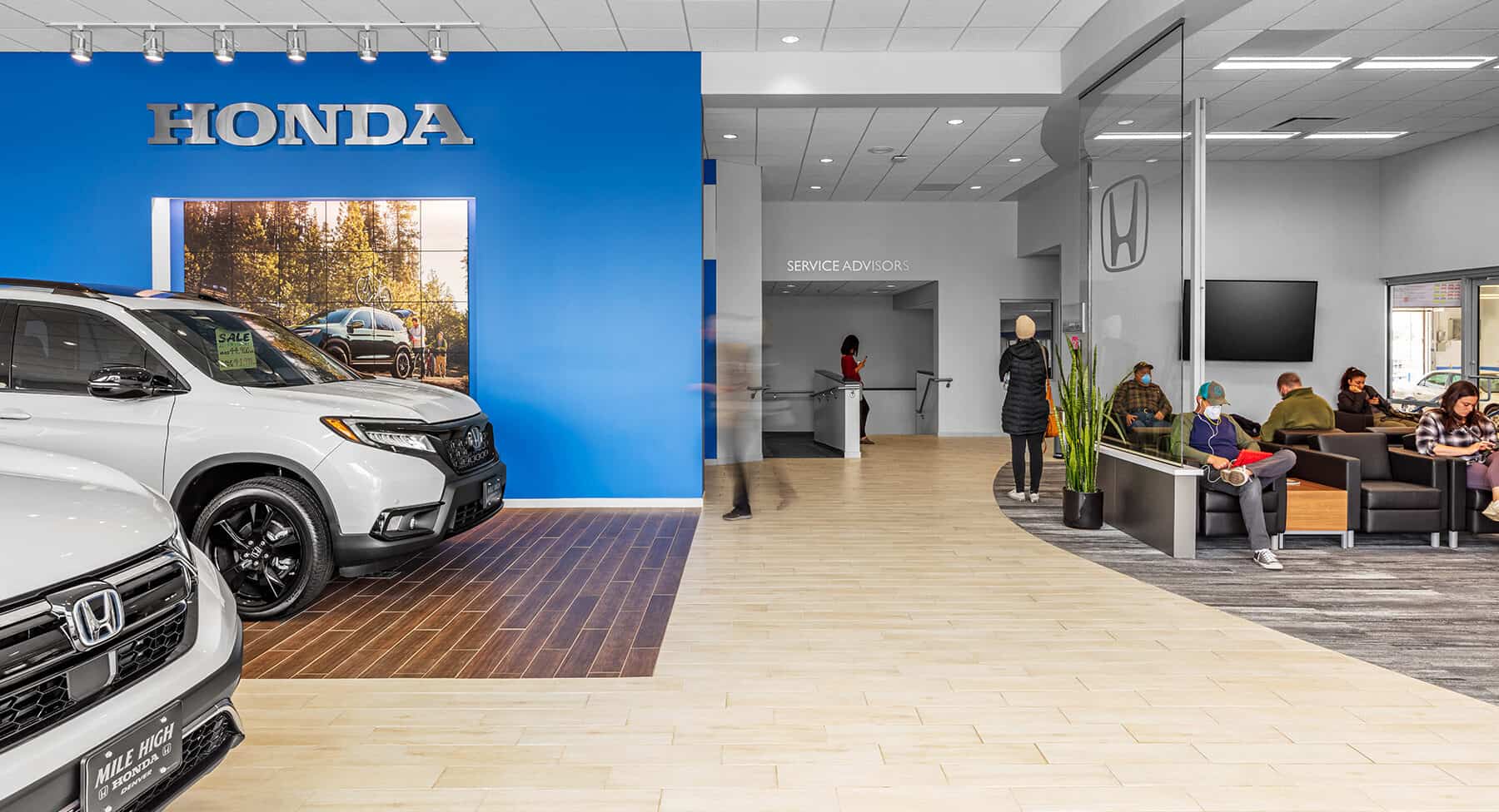 Two new cars sitting in the showroom while customers wait in the high design waiting room.