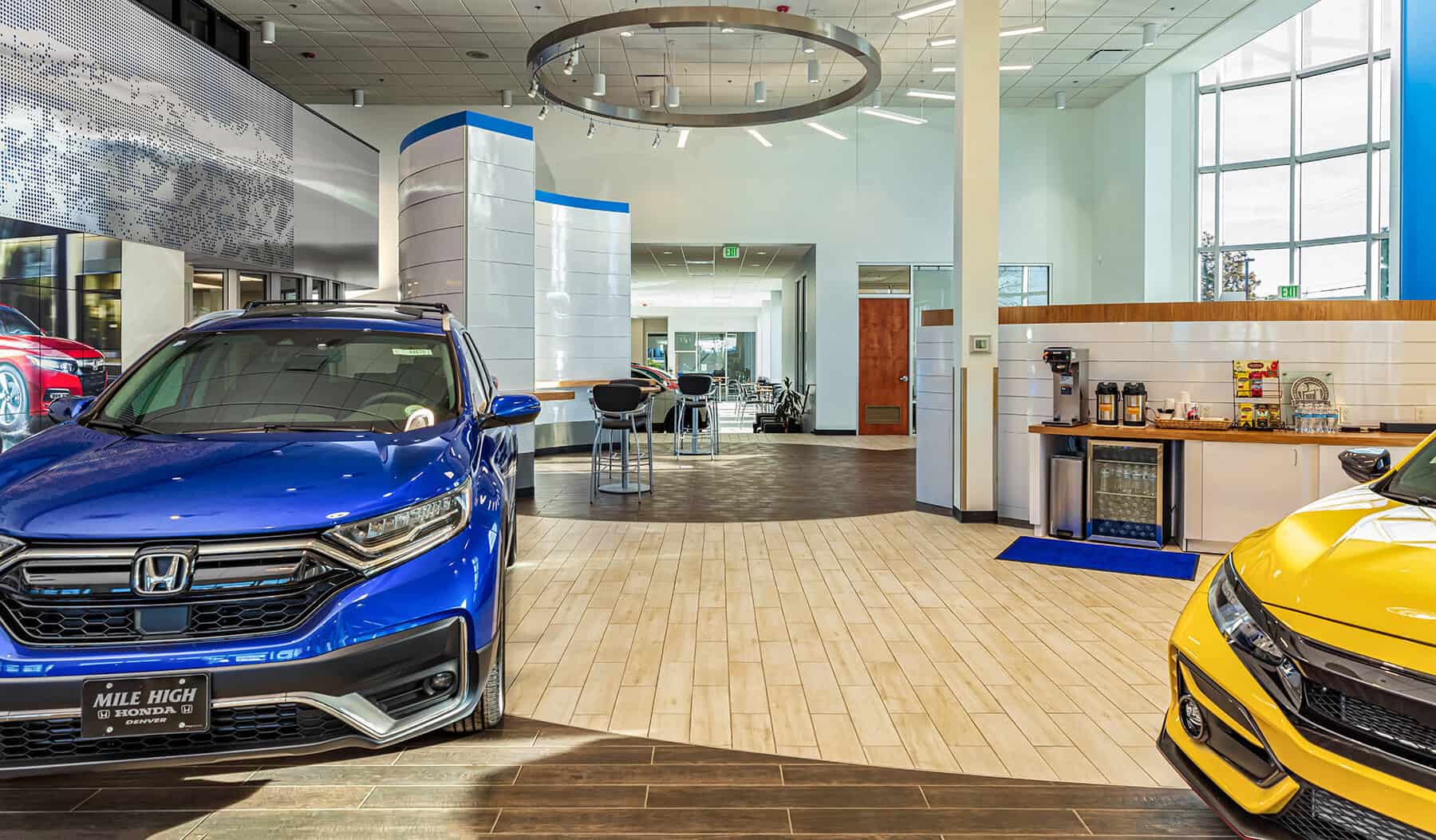 A blue and yellow car sitting in the show room with customer amenities available for their comfort.